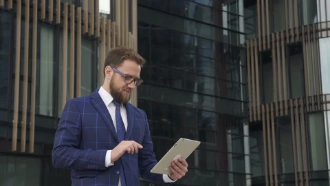 Handsome businessman is using tablet, standing on background of office building. Stock Footage 92474539