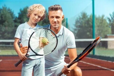 Handsome caring daddy hugging his son before playing tennis Stock Photos