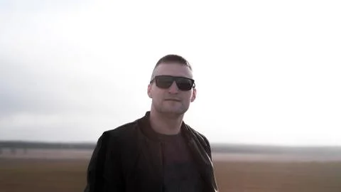 Handsome casual man wearing sunglasses standing outside in a grass field Stock Photos