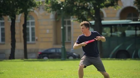 Handsome caucasian man playing red frisbee outdoors Stock Footage 75035884