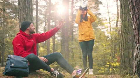 Handsome caucasian man sitting on log in woods and looking at offline map on Stock Footage 147065971