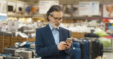 Handsome Caucasian man texting message on mobile phone in supermarket. Stylish Stock Footage 135342225