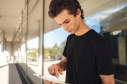 Handsome Caucasian man using digital tablet while standing at college campus Stock Photos