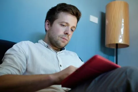 Handsome caucasian man using his tablet sitting on a couch Stock Photos