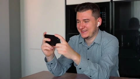 Handsome caucasian man using phone and headphones watching video Stock Footage 153976330