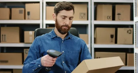 Handsome Caucasian postman sitting at desk and working at computer in postal Stock Footage 125218445