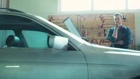 Handsome Caucasian serviceman standing behind car in garage or auto service Stock Footage 276904195