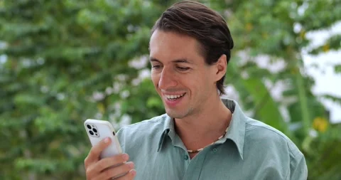 Handsome Caucasian young man using a smartphone, scrolling, browsing the web and Stock Footage 209870376