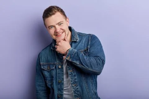 Handsome cheerful young man smiling and touching his chin Stock Photos