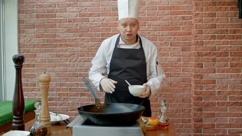 Handsome chef preparing pan with batter and talking to camera Video stock 74933898