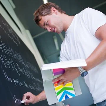 Handsome college student solving a math problem during math clas Stock Photos