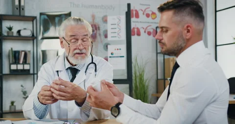 Handsome concentrated bearded man taking bottles with pills from experienced Stock Footage 160847140