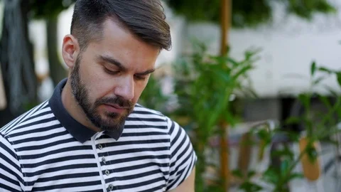 Handsome concentrated young bearded man in stylish T-shirt in depth read a book  Stock Footage 112353441