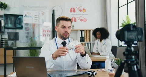 Handsome confident experienced modern bearded doctor showing into camera how to Stock Footage 159805859