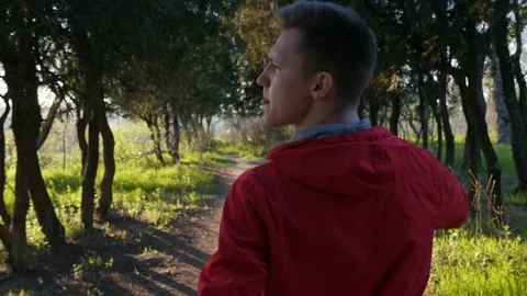 Handsome cool boy goes confidently through the beautiful park on sunset. Green Видео 106730904