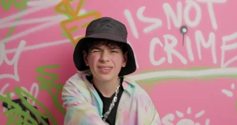 Handsome cool guy wears hat and metal chain makes rap gesture dances to favorite Stock Footage 151197331