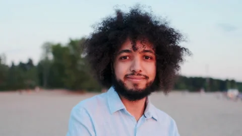 Handsome Curly Hispanic Man Looking in Camera while Standing Alone in Park Stock Footage 148552491