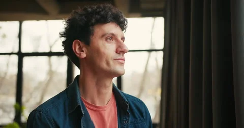 Handsome curly man posing and smiling, looking at camera in modern coworking Stock Footage 323428071