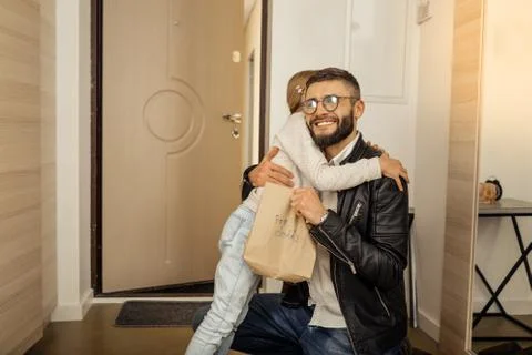 Handsome dark-haired bearded man in eyewear hugging his daughter warmly Stock Photos