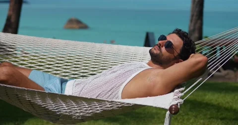 Handsome dark-haired bearded young man with tanned skin, puts on sunglasses Stock Footage 220597069