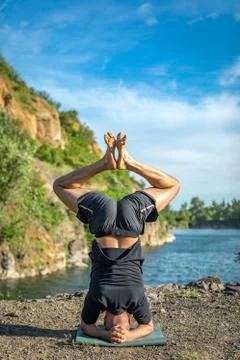Handsome dark haired man with beard practicing yoga. Young man standing on hi Stock Photos