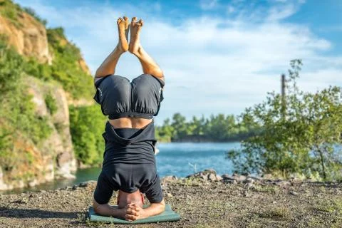 Handsome dark haired man with beard practicing yoga. Young man standing on hi Stock Photos