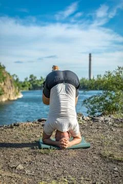 Handsome dark haired man with beard practicing yoga. Young man standing on hi Stock Photos