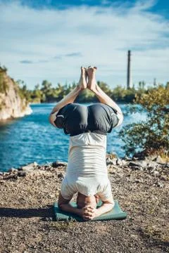 Handsome dark haired man with beard practicing yoga. Young man standing on hi Stock Photos