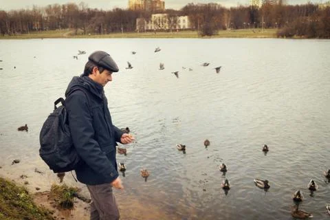 Handsome dark-haired middle-aged man in jacket, cap and backpack Stock Photos