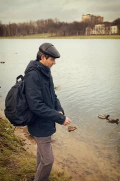 Handsome dark-haired middle-aged man in jacket, cap and backpack Stock Photos