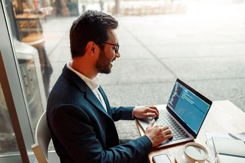Handsome developer programmer freelancer in glasses working on project in cafe Stock Photos