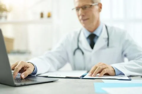 Handsome doctor using modern notebook in clinic Stock Photos