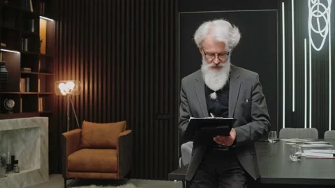 Handsome elderly businessman writes at the tablet and looks at camera smiling Stock-Footage 166968087