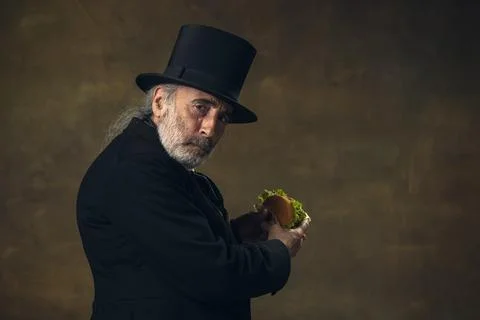 Handsome elderly gray-haired man, gentleman, aristocrat or actor eating fast Stock Photos