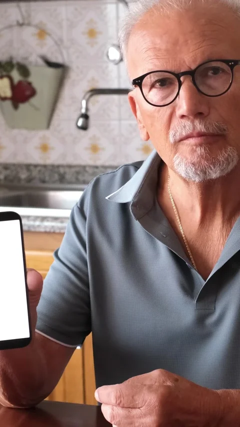 Handsome elderly man sitting at a table using his mobile phone and then showing Stock Footage 344389776