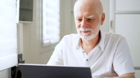 Handsome elderly senior man working on laptop computer at home. Remote freelance Stock Footage