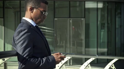 Handsome elegant black businessman using cell phone: texting a message or email Stock-Footage 58330282