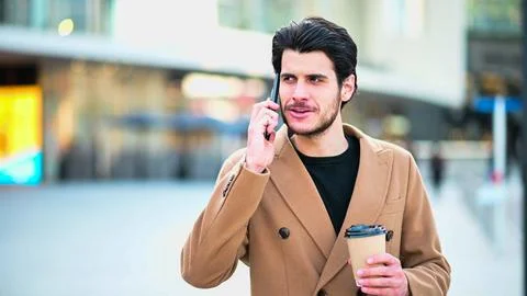 Handsome elegant dressed man talking on the phone and holding a cup of coffee Fotos Stock