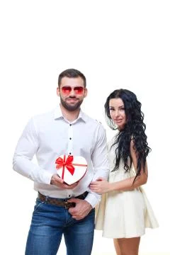 Handsome elegant guy is presenting a heart shaped gift to his beautiful Stock Photos