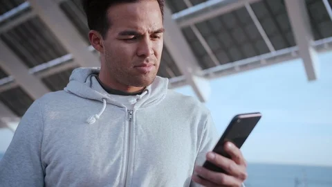 Handsome emotional guy using social media application on smart phone device Stock Footage 105755248