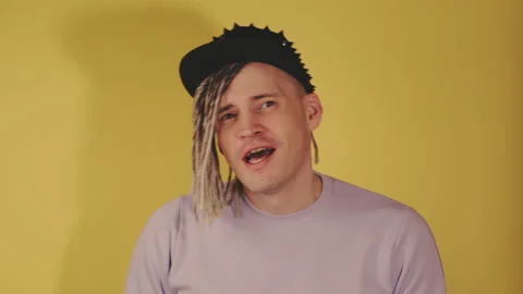 Handsome energetic man with blonde dreadlocks in black cap dancing, singing in Stock Footage 199120108