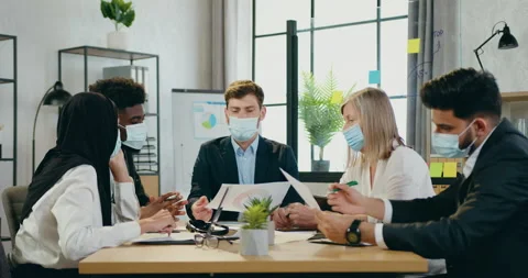Handsome experienced ceo in protective mask holding business meeting with his Stock Footage 159599029