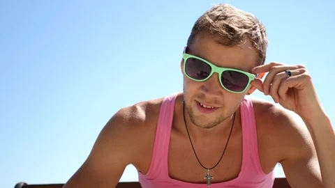 Handsome fashionable guy with sunglasses in a pink T-shirt looks at the camera Stock Footage