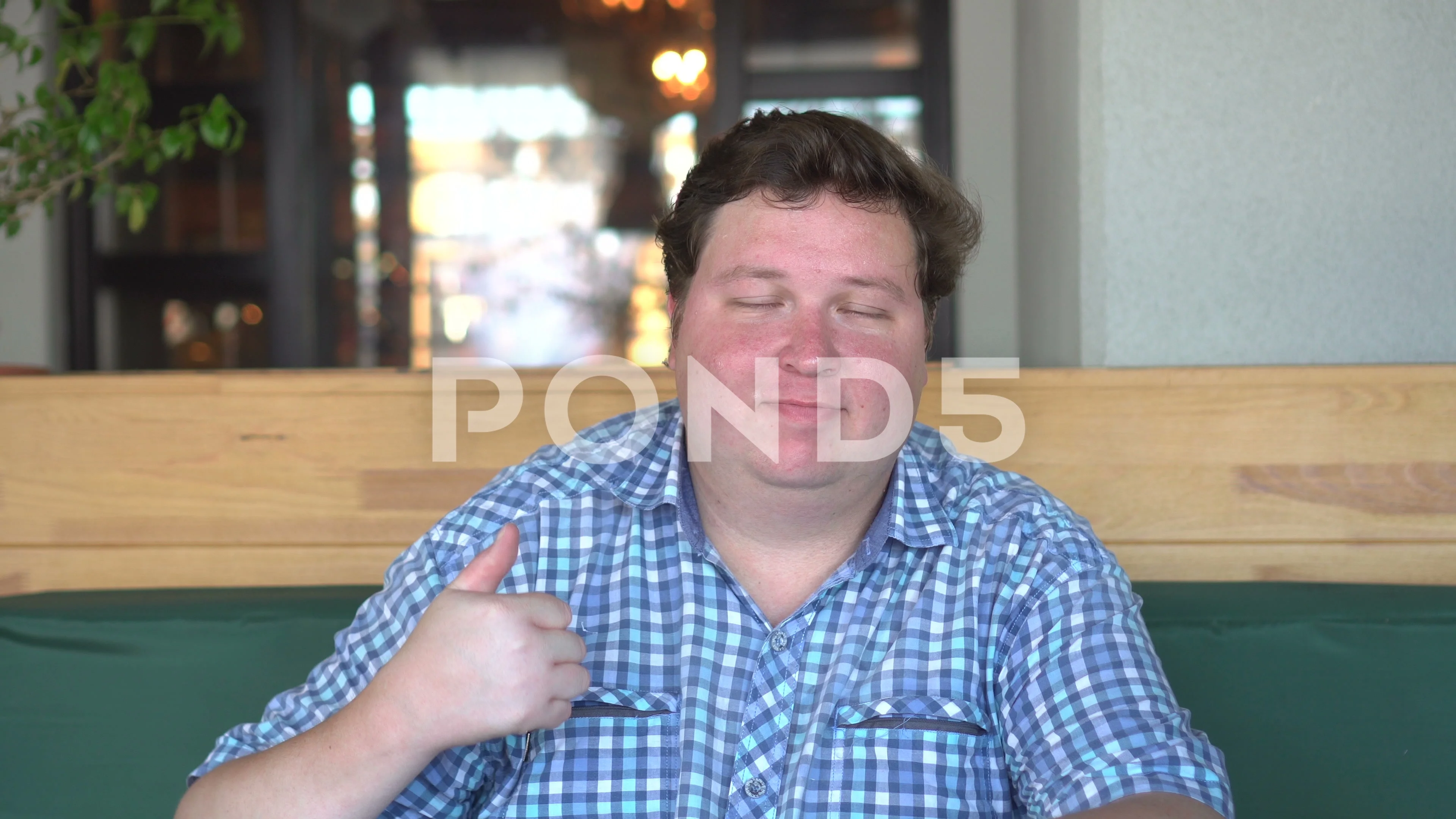 A handsome, fat man with big body shows thumbs up in the cafe or restaurant