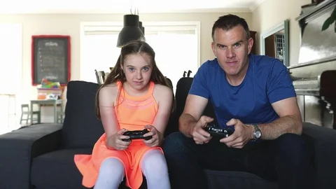 Handsome father and his cute little daughter are playing game console and Stock-Footage 80313845
