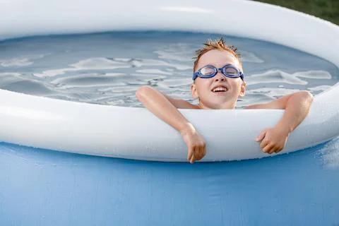 A handsome five-year-old boy in swimming gounts and disheveled hair bathes in a Stock Photos