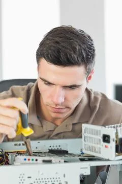 Handsome focused computer engineer repairing open computer Stock Photos