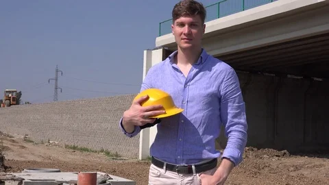 Handsome foreman holding helmet hardhat in hand smiling happy constructor layout Stock Footage