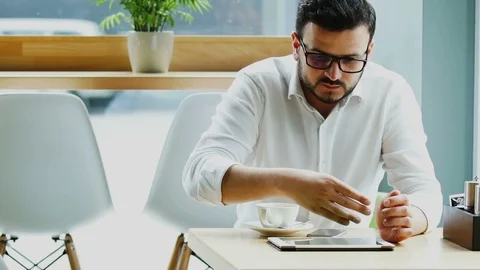 Handsome freelancer in formal clothes scrolling his tablet on the table in cafe Stock Footage 112990432