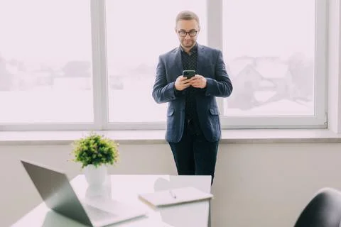 Handsome freelancer working remotely from home. He is using phone. Stock Photos